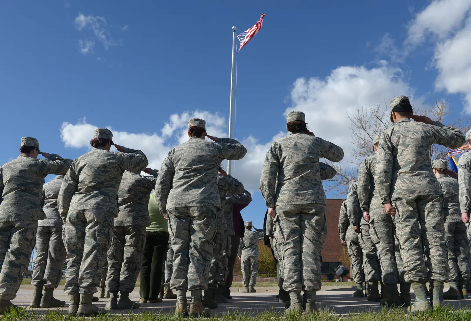 Women airmen in uniform salute the American flag during a Women's History Month retreat